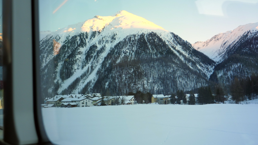 Snowcapped Swiss Alps and mountain village from inside Glacier Express in Switzerland Royalty-Free Stock Footage #1057701475
