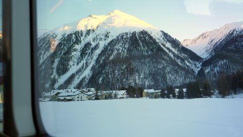 Snowcapped Swiss Alps and mountain village from inside Glacier Express in Switzerland