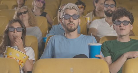 Portrait of rude young man talking on the phone in cinema ignoring people. Visitors scolding Caucasian guy making noise in movie theatre. Ill-mannered man in 3d glasses. Cinema 4k ProRes HQ.