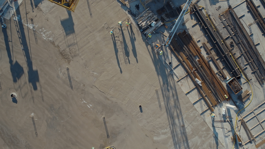 Aerial Flight Over a New Constructions Development Site with High Tower Cranes Building Real Estate. Heavy Machinery and Construction Workers are Employed. Top Down View at Contractors in Safety Hats. Royalty-Free Stock Footage #1057704832