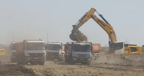 Bucharest, Romania - August 18, 2020: Earthmovers and lorries on the construction site of a highway.