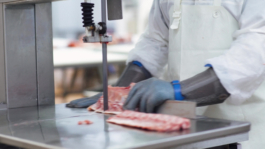 Meat processing plant, butcher cuts pork carcasses, meat production and food industry, the process of harvesting meat, butcher cuts the meat into pieces. Royalty-Free Stock Footage #1057706860