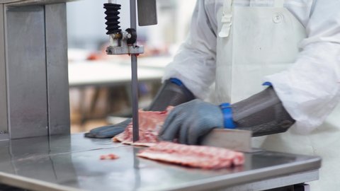 Meat processing plant, butcher cuts pork carcasses, meat production and food industry, the process of harvesting meat, butcher cuts the meat into pieces.