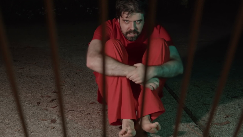 An angry scary prisoner glaring through prison bars