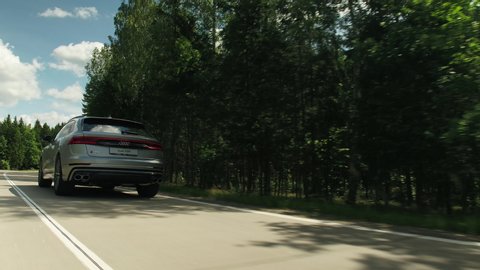 Russia, Sochi - August, 2020: close-up cinematic shot of a brand new Audi SQ8 driving on country road in forest in the morning at sunny day