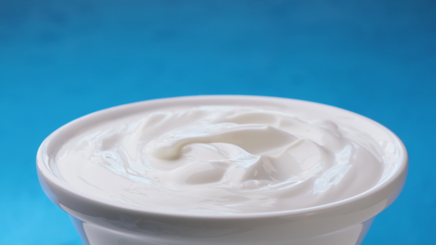 Bowl of sour cream on blue background, greek yogurt with spoon Royalty-Free Stock Footage #1057719112