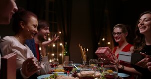 Group of multiethnic friends celebrating christmas together, talking, cheering and handing each other special gifts - real people, holiday, celebration concept 4k footage