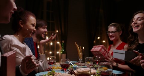 Group of multiethnic friends celebrating christmas together, talking, cheering and handing each other special gifts - real people, holiday, celebration concept 4k footage 库存视频