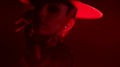 Beautiful hat dressed girl dancing latin dance . Professional female dancer dancing flamenco , rumba or salsa on red background with lines . Spanish dance movements . Shot ARRI ALEXA Cinema Camera .