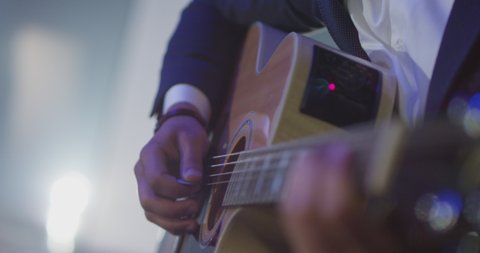 4K Footage of male hands playing acoustic guitar. Guitarist plays in classical guitar on stage in concert . Close up . Guitar strings . Rock music band . Shot on ARRI ALEXA movie camera in slow motion
