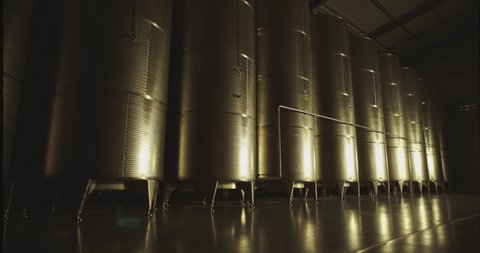 Large stainless steel wine distilling tanks . Silos for wine or beer fermentation . Steel barrels for fermentation of wine in winemaker factory . Shot on Arri camera with dolly move and strobe light .