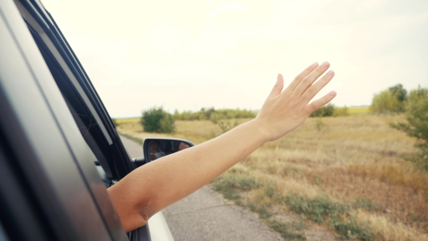 Happy free girl put her hand out and in the car window. concept travel road hand out of the window. the girl touches the wind with her hand the view from the car window. freedom and journey happiness | Shutterstock HD Video #1057736545