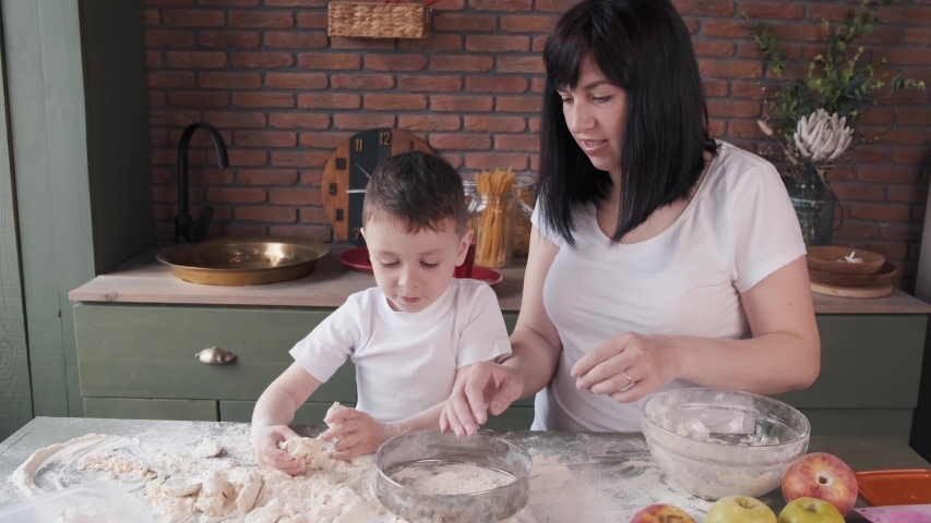 Family in a kitchen. Beautiful mother with little son. Little boy playing wit a dough. | Shutterstock HD Video #1057744678