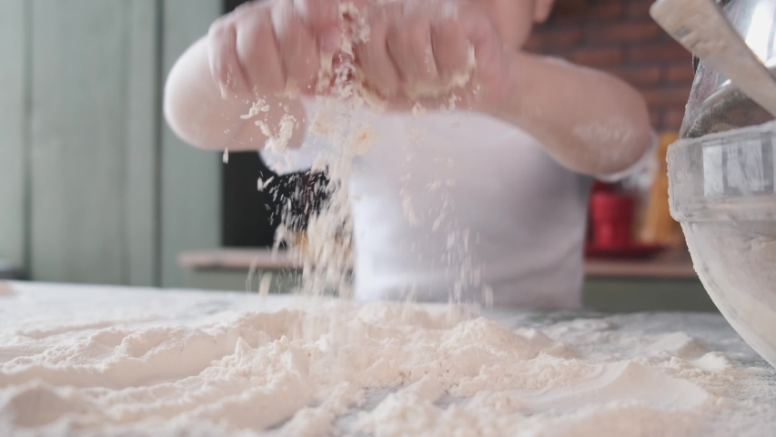 Child in a kitchen. Little boy with a dough. Kid in a white t-shirt.