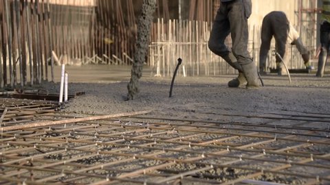 Workers Pouring Concrete reinforcement into a floor metallic structure base low angle 