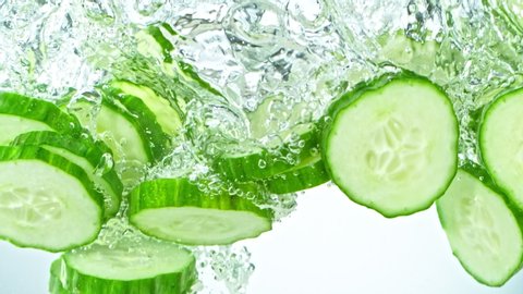 Super Slow Motion Shot of Cucumber Slices Falling into Water on White Background at 1000fps.
