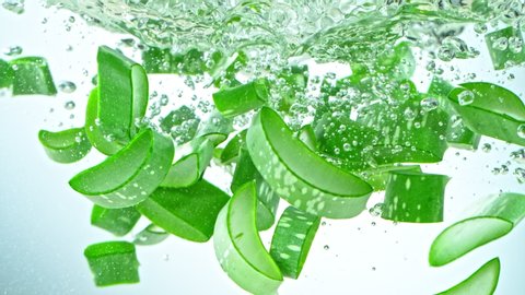 Super Slow Motion Shot of Aloe Vera Cuts Falling into Water on White Background at 1000fps.