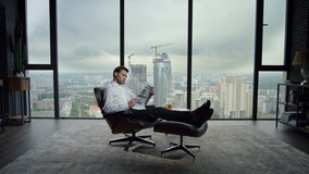 Focused businessman resting in office chair with newspaper. Male top manager reading daily newspaper in office with city view. Smiling business man looking at article in financial newspaper at home - Powered by Shutterstock - Get 15% off with code: PIKWIZARD15
