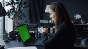 Business woman calling video on laptop computer with green screen in office. Female entrepreneur having video conference online at remote workplace. Businesswoman gesturing during video conversation