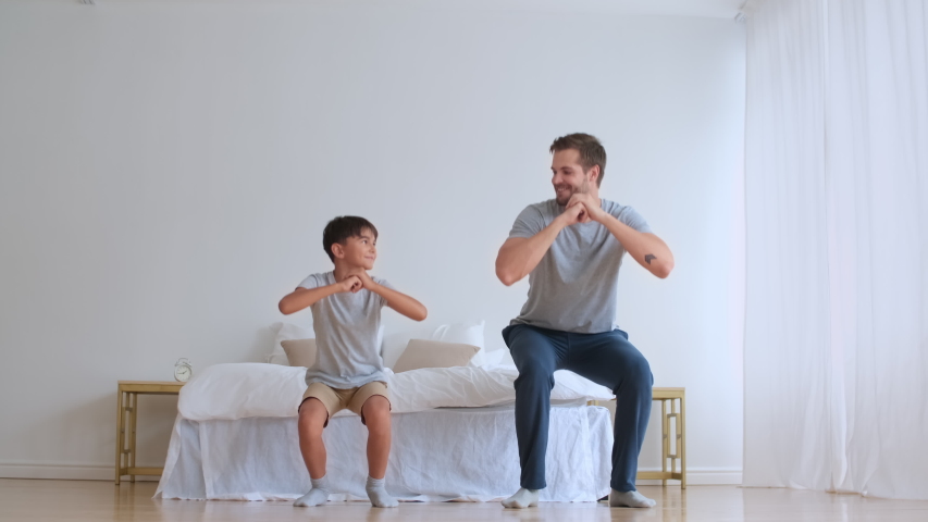 Family fitness at home, Father coach, Sports kid, Fun gymnastics. Dad and son doing physical exercise squatting together while standing on the floor at home Royalty-Free Stock Footage #1057750687