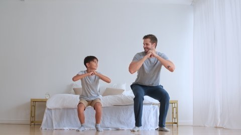 Family fitness at home, Father coach, Sports kid, Fun gymnastics. Dad and son doing physical exercise squatting together while standing on the floor at home