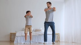 Father Day,Family fitness at home, Father coach, Sports kid, Fun gymnastics. Sportive dad and son doing physical exercise squatting together while standing on the floor at home