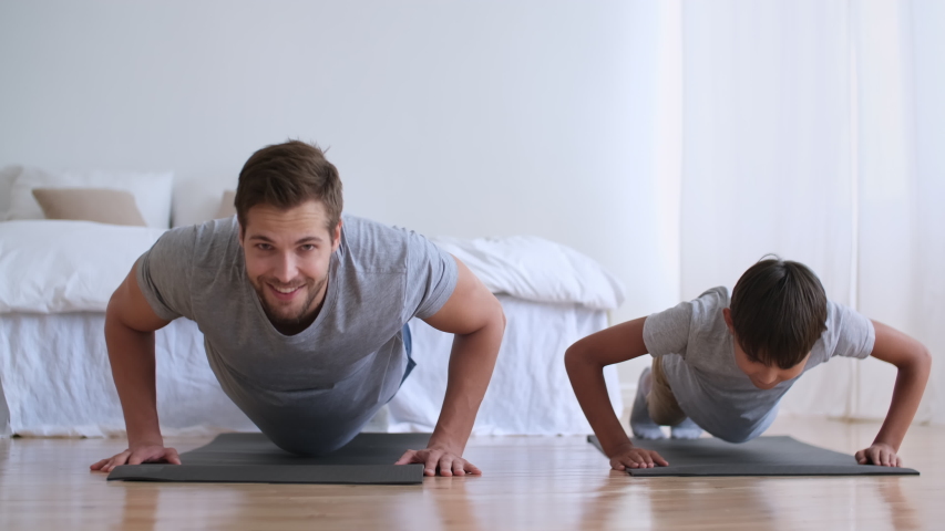 Father Day,Family fitness at home, Father coach, Sports kid, Fun gymnastics. Dad and son are doing physical exercise pushing up from the floor at home | Shutterstock HD Video #1057750783