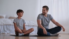 Father Day,Family fitness at home, Father coach, Sports kid, Fun gymnastics. Cheerful man and boy go in for sports at home while sitting on the floor