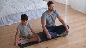 Father Day,Family fitness at home, Father coach, Sports kid, Fun gymnastics. Man and boy relax in yoga pose at home while sitting on the floor