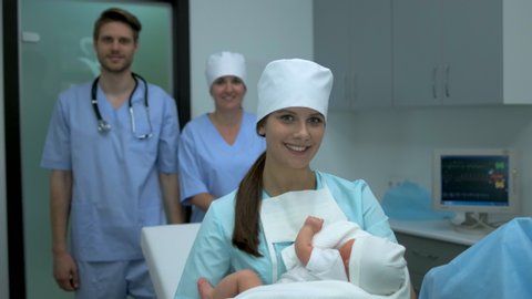 Childbirth pregnancy, Newborn baby after birth labor in hands of medical staff. Midwife nurse, obstetrician gynecologist in maternity hospital clinic, doctor holding new born child in arms 4 K slow-mo