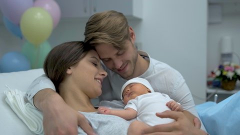 Happy family. Newborn baby resting in mother and father arms. Parents right after delivery in maternity hospital. Woman holding her new born child after birth labor. Childbirth motherhood, 4 K slow-mo