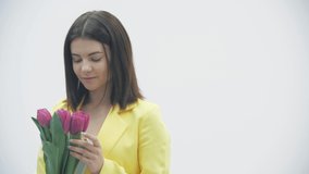 Young female enjoying a bouquet of tulips over white background.