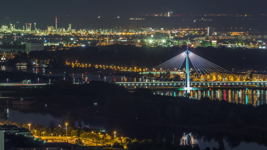 Aerial panoramic view over Vienna city with skyscrapers, Donaustadt Bridge and a riverside promenade night timelapse in Austria. Illuminated skyline from Danube Tower viewpoint