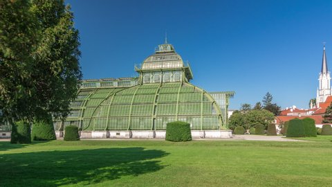 The Palmenhaus Schoenbrunn timelapse hyperlapse - a large greenhouse in the park Schoenbrunn in Vienna, Austria. Green lawn with flowerbed around