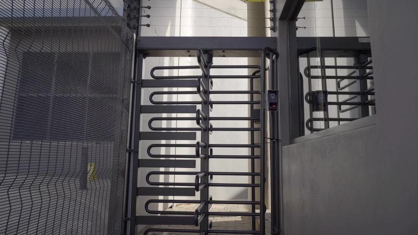 Tracking shot business entrance with high-security guardhouse, automated turnstile and biometrics.