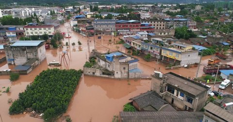 Leshan, SiChuan/China-Aug 18th 2020: Aerial view of small town been Flooded Chinese neighbourhood Homes, houses overflowing water people walking car driving in the muddy water 