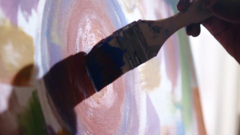 Abstract colorful painting on canvas created by black artist, using wide brush and bright colors, painting blue circle in the center of canvas, Close up, Slow motion.