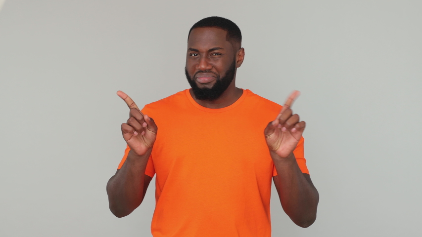 Young confident bearded african american man in orange basic casual t-shirt look camera pointing fingers himself ask say who me no thanks i do not need it isolated on gray color background in studio | Shutterstock HD Video #1057782205