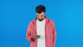 Young male looking at social media accounts on his phone.Close up.Slow motion 4K video. Blue background.