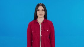 What.? Tough strict brunette woman points to camera and looks angrily with suspicion, blaming failure, choosing the guilty person. Indoor studio shot isolated on blue background.Slow motion 4K video. 