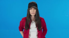 Young woman profile portrait on blue background. Young woman wearing a hat. Cool girl.Slow motion 4K video. Blue background.
