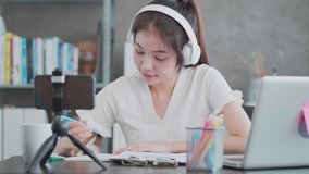 MS shot : Asian woman online learning via smartphone at home. Concept of New normal Healthy Lifestyle, remote working, online learning at home while quarantine from corona virus or covid-19 pandemic.
