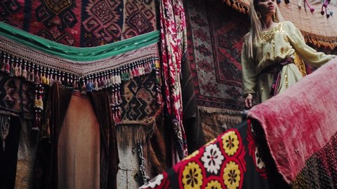Fashion blonde beautiful girl in old carpet shop. Turkey. Oriental carpet. Persian shop. Tourists in store.