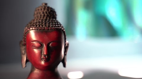 Close up of buddha red Idol face meditating with dark background and wind