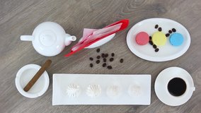 Top view spinning video of coffee cup with macaroons and candies with kettle and cigar in ashtray.