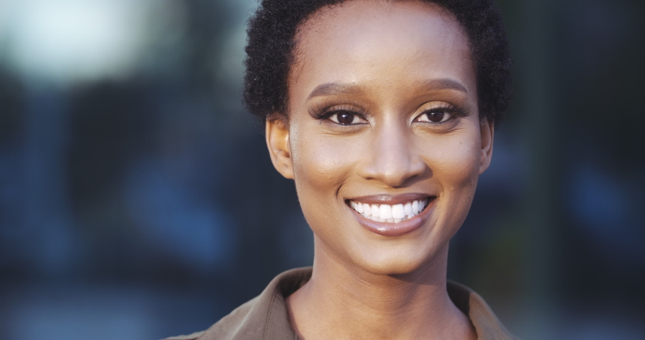 Portrait of beautiful African American ethnic woman looking at camera, smiling toothy, happy eyes, short hair, friendly female face. Close up of mixed race lady standing on street, feeling comfortable | Shutterstock HD Video #1057791529