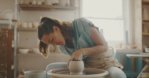 Young artist in the pottery studio making bowl with her hands, handmade creative artist