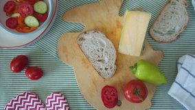 Top view woman's hand spreads butter on piece fresh bread, woman prepares sandwich with cheese and tomatoes, healthy snack, healthy food, vegetarian lunch