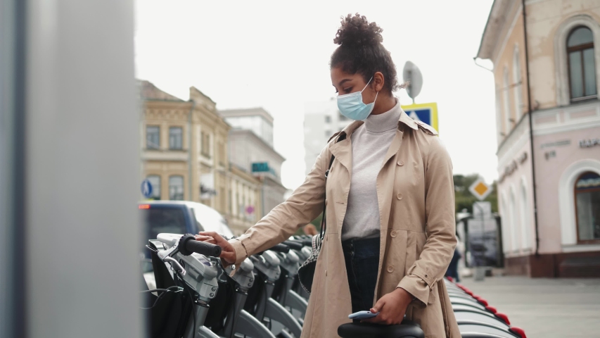Safe travel. Black Woman take Electric scooter or bike bicycle sharing parking lot, tourist phone application. New sharing business project started in city, eco transportation, post covid safe life.