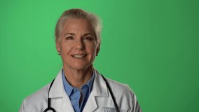 Portrait of experienced gray haired female doctor listening and talking to a patient. Shot on green screen.